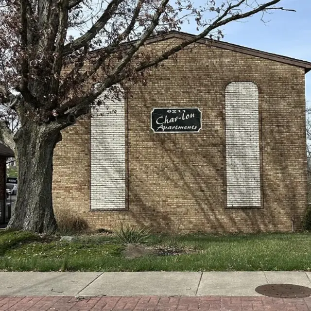 Char-Lou Apartments Building A brick wall of a building with a sign that reads 'Char-lon Apartments,' flanked by two blank sections where windows may have been.