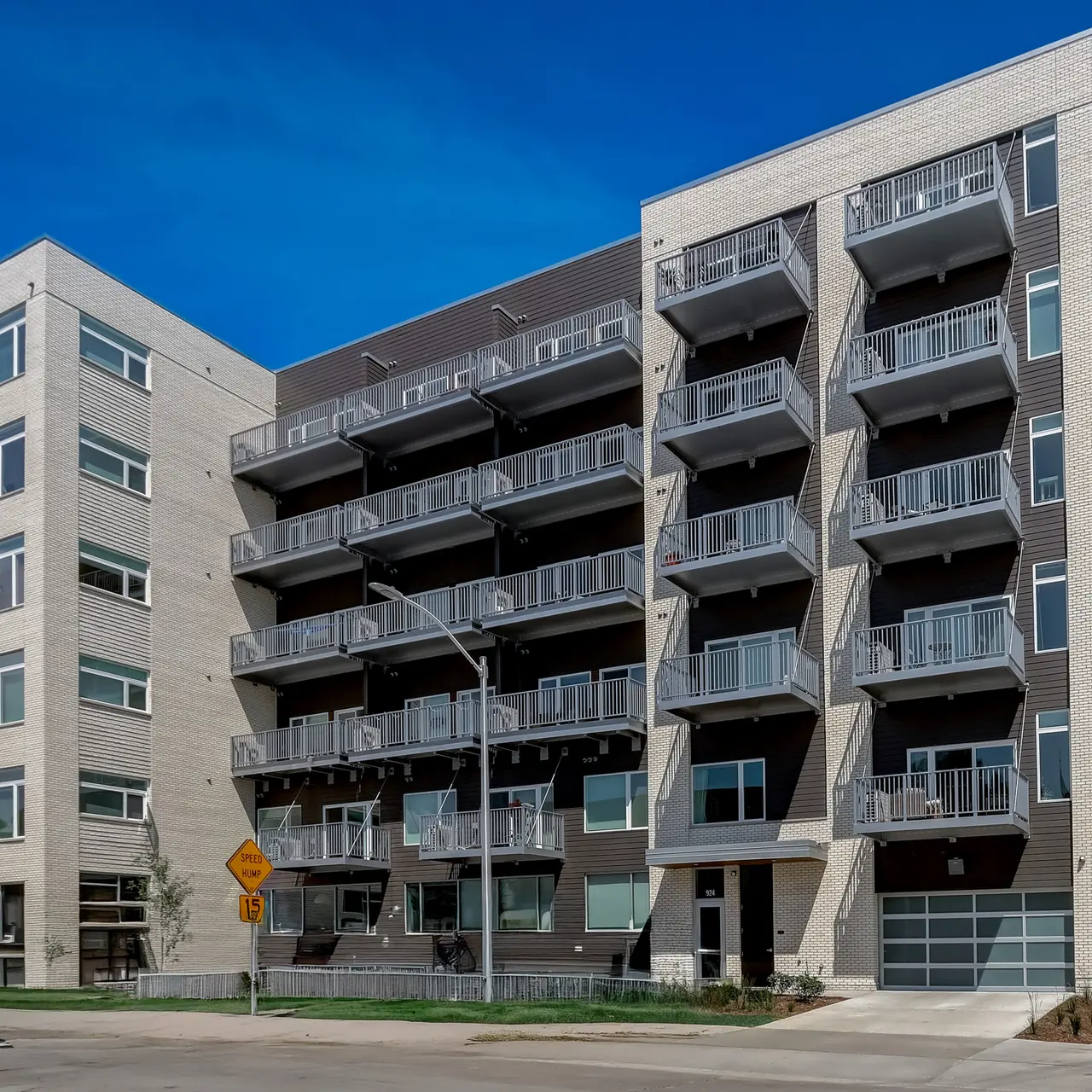 Modern Apartment Complex A modern multi-story apartment building featuring multiple balconies and large windows against a clear blue sky.