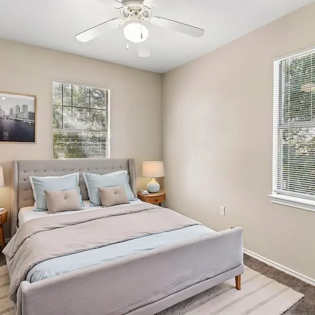 Modern Bedroom Interior A modern bedroom featuring a light gray bedspread, bedside tables with lamps, and a large window letting in natural light.