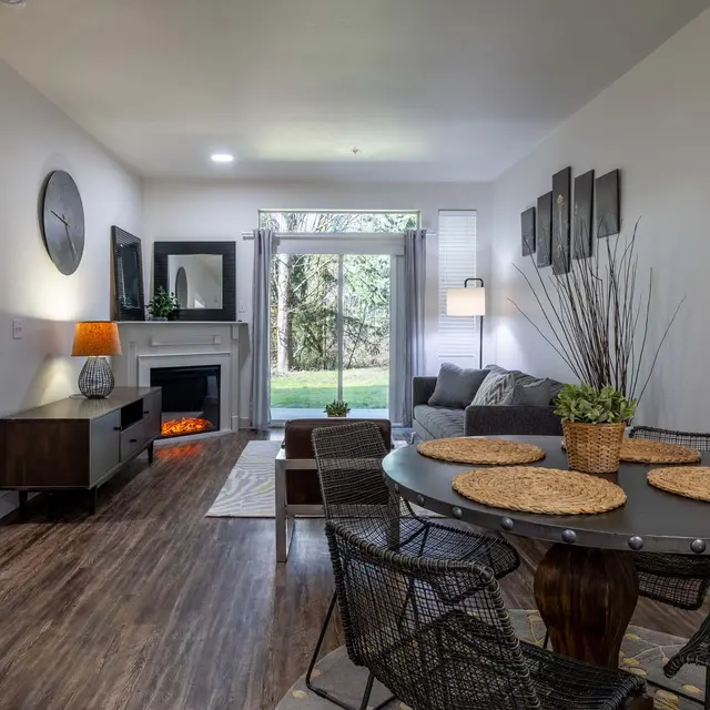 A bright and modern living space featuring a dining area, comfortable seating, and a view of the outdoors through large windows.