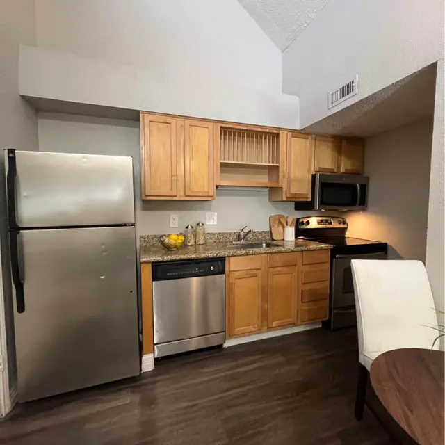 A compact kitchen featuring wooden cabinets, stainless steel appliances, and a granite countertop.