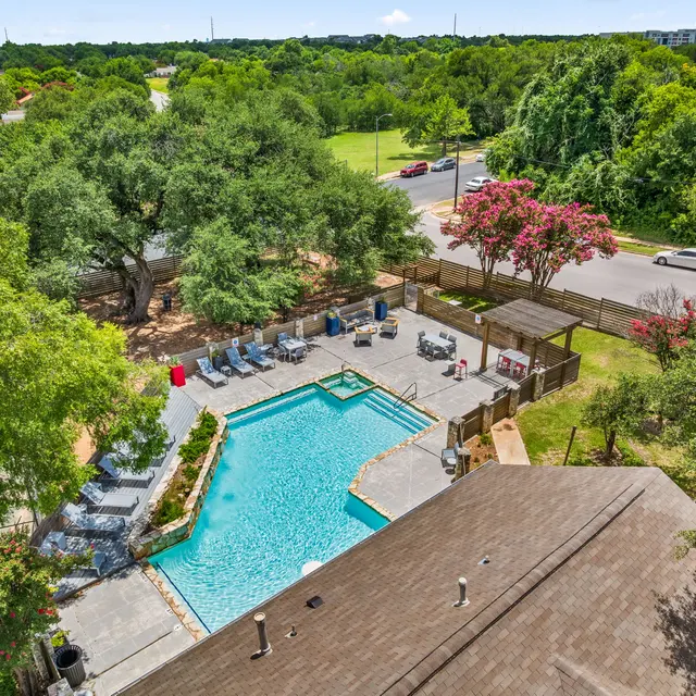 Aerial view of a residential area featuring a swimming pool surrounded by lounge chairs and lush greenery.
