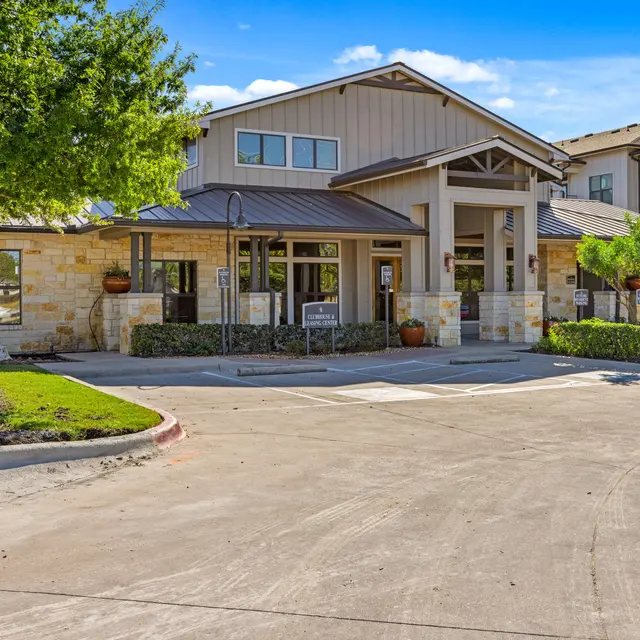 Exterior view of an apartment complex entrance with landscaped grounds.