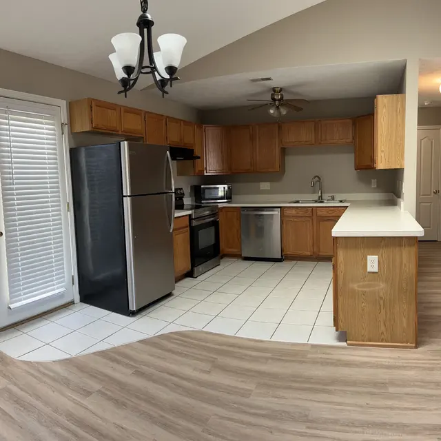 A modern kitchen with wooden cabinets, stainless steel appliances, and a tile floor.