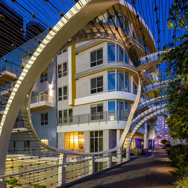 Modern Architecture at Night A modern building illuminated at night, featuring unique architectural design and a pathway lined with greenery.