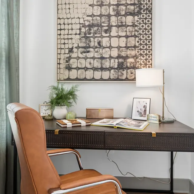 Cozy Home Office Corner A cozy home office corner featuring a dark wooden desk with a modern lamp and decorative items, a stylish chair, and a piece of abstract wall art.