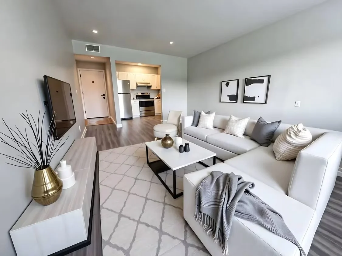 Prime Gardenside Modern living room featuring a light-colored sectional sofa, sleek coffee table, decorative pillows, and a flat-screen TV.