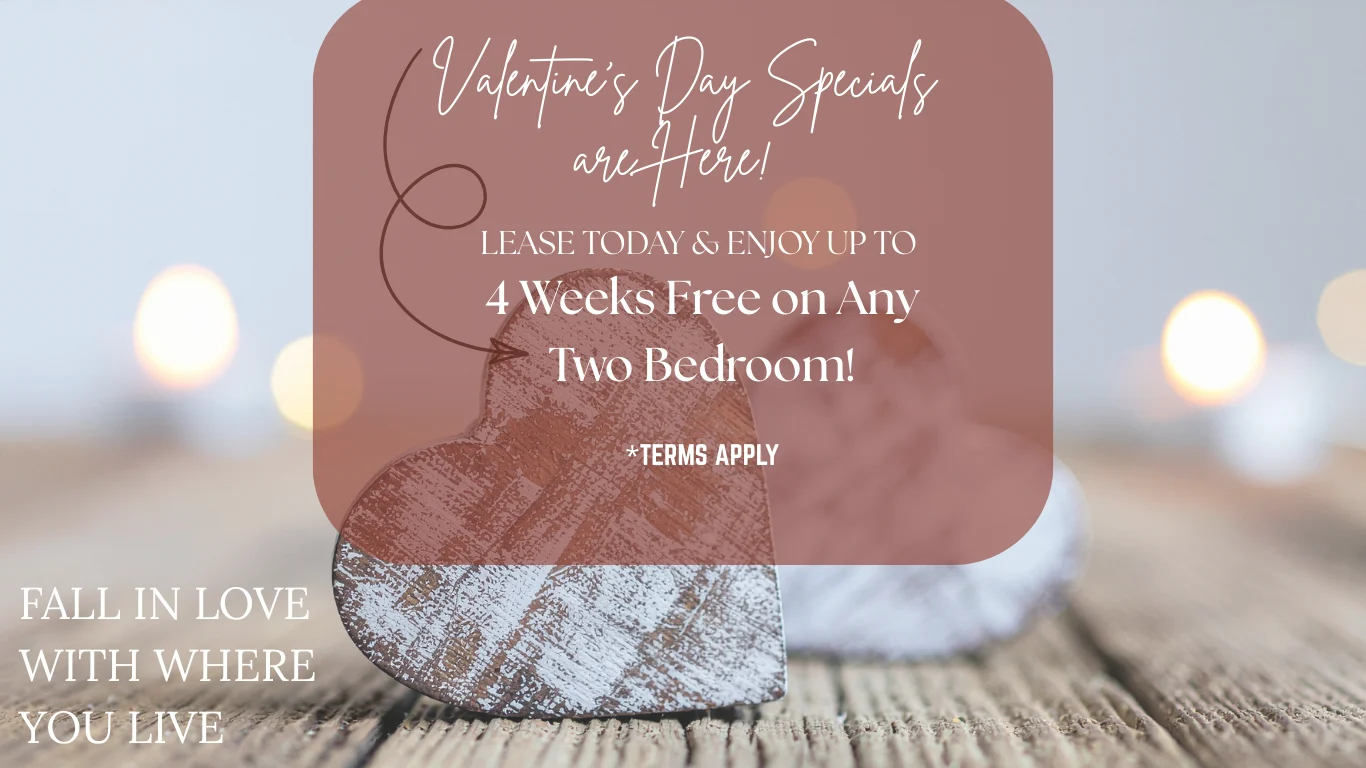 A promotional graphic for Valentine's Day specials featuring a wooden heart decoration, soft lighting, and a wooden surface. The text indicates a leasing offer with terms and conditions.