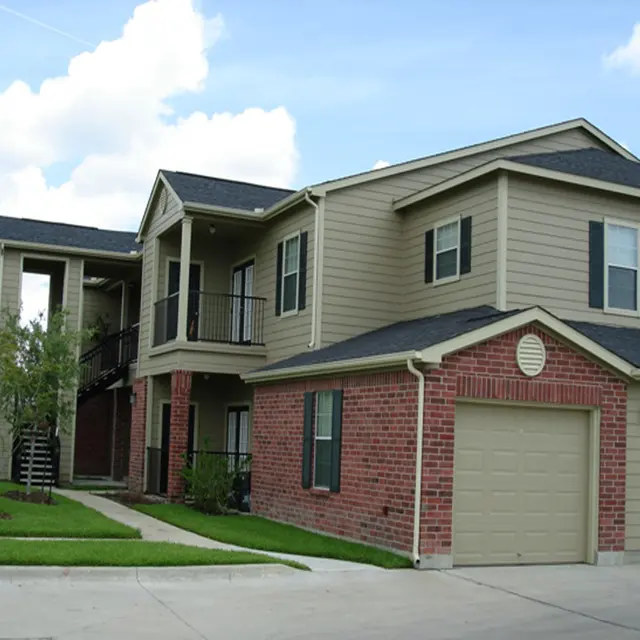 Exterior view of a modern apartment building featuring brick and siding architecture with balconies and a garage.