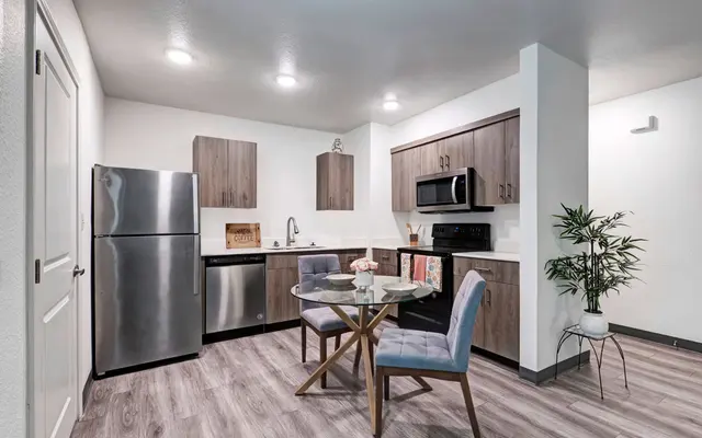 Modern Kitchen Design A modern kitchen featuring stainless steel appliances, wooden cabinetry, and a small dining table with two chairs in a well-lit space.