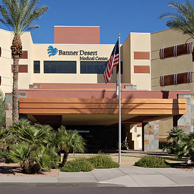 Facade of Banner Desert Medical Center with palm trees and an American flag in front.