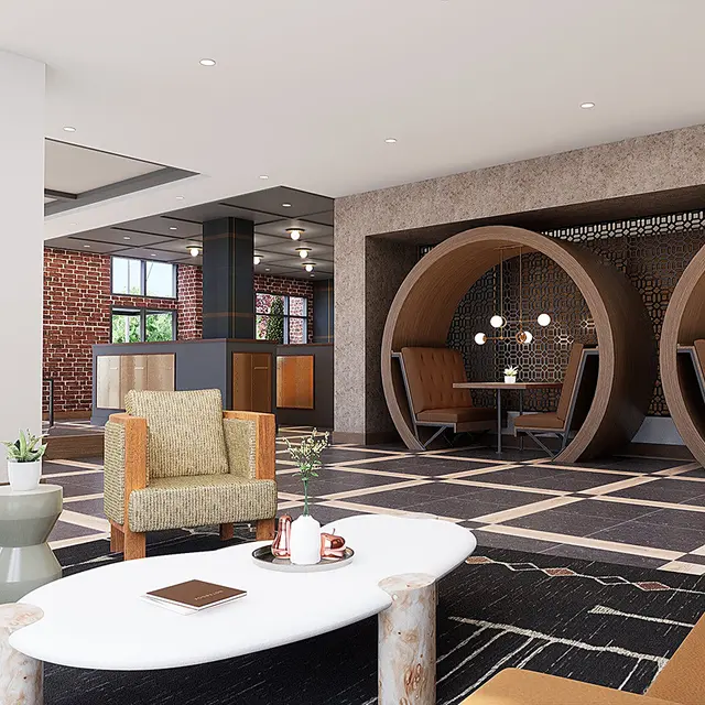 A modern lobby interior showcasing stylish seating arrangements. There are two unique circular seating pods along one wall, and a mix of contemporary furniture including a coffee table and armchairs. Large windows allow natural light to flood in, enhancing the open and inviting atmosphere.