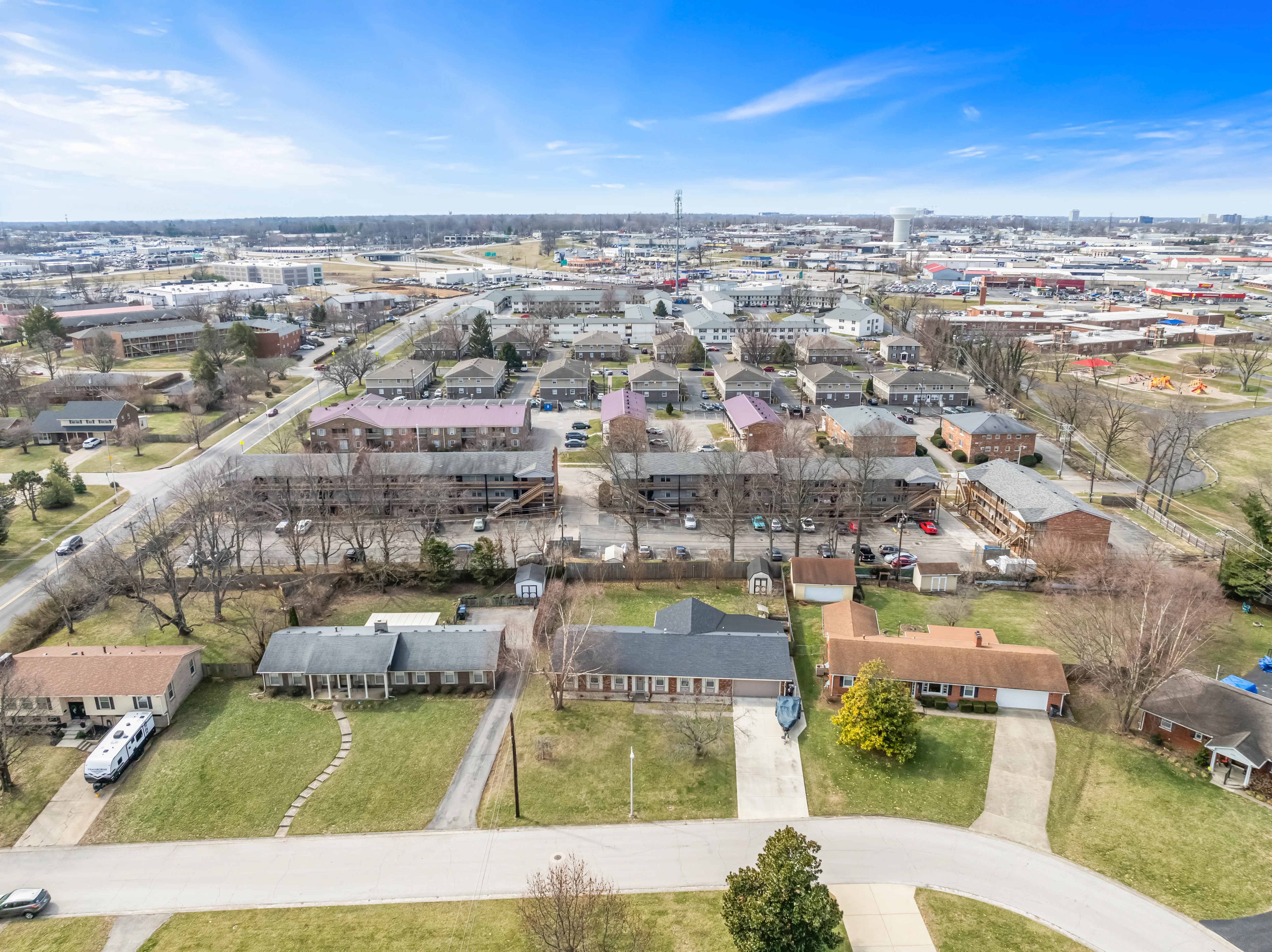 Aerial View of Suburban Neighborhood Aerial view of a suburban neighborhood showcasing rows of houses, roads, and nearby commercial areas in the distance.