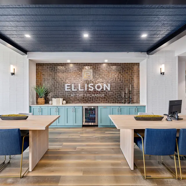 Modern office lobby with two work desks, blue chairs, and a decorative wall featuring the name 'ELLISON' against a stylish background.