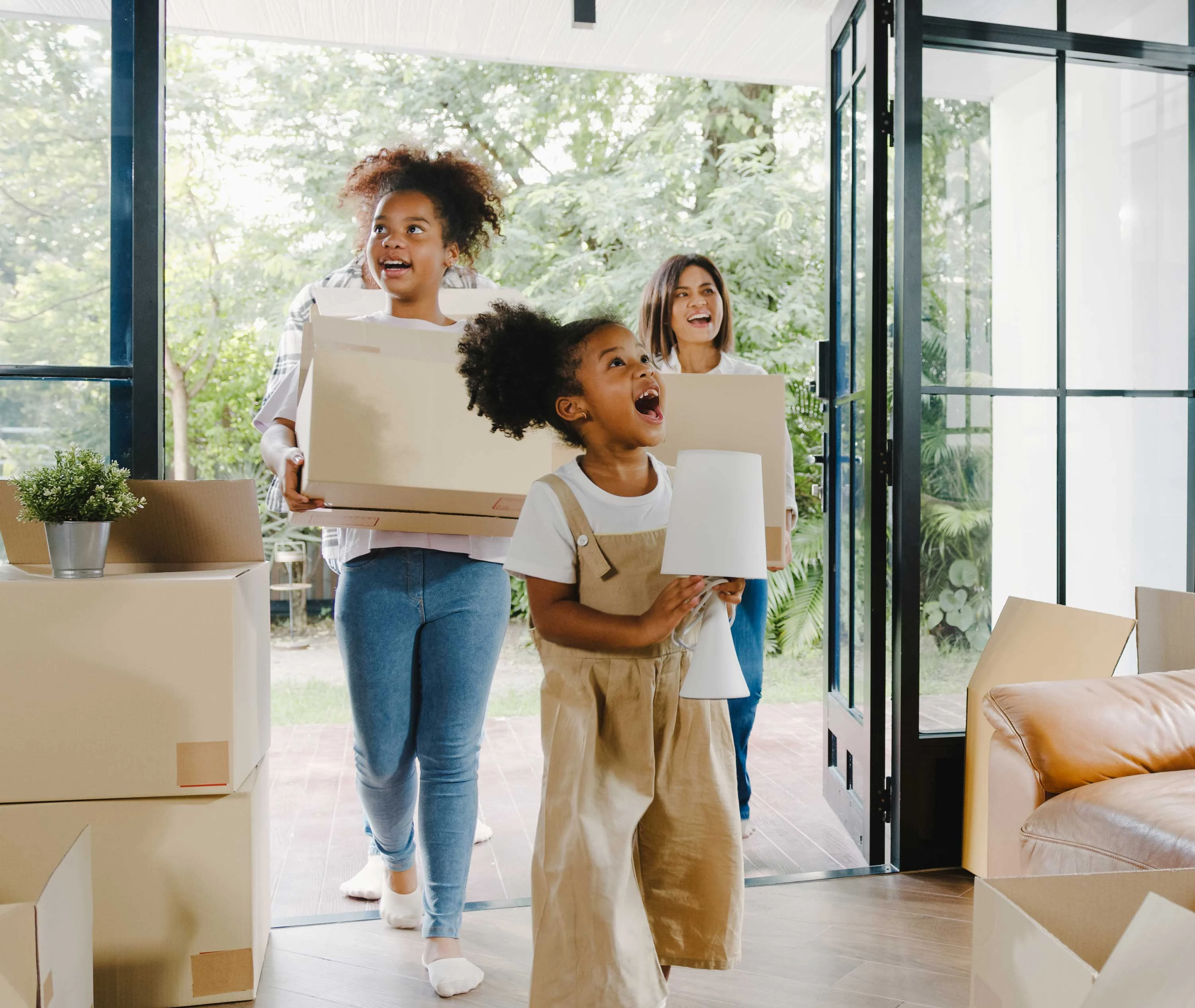 Happy Moving Day Three children carrying boxes in a bright, airy room filled with moving boxes.