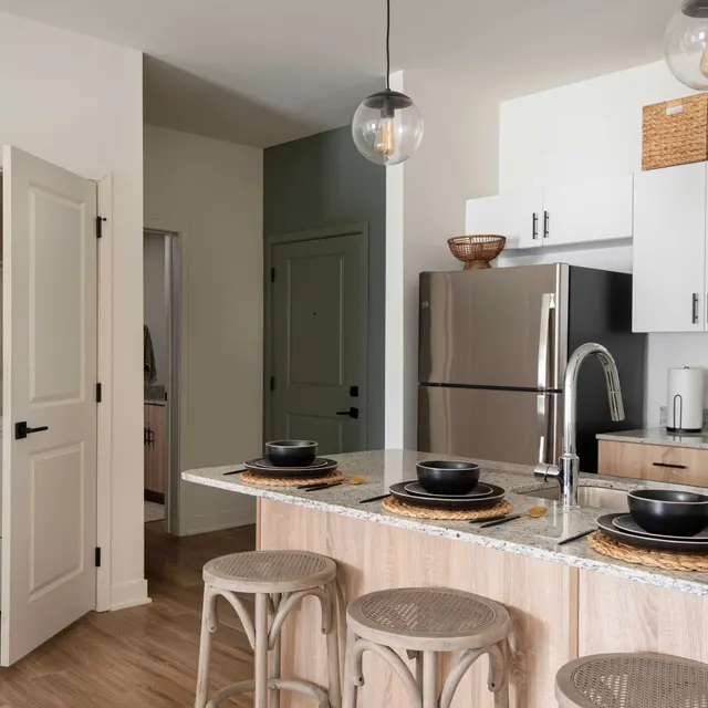 A modern kitchen featuring a large island with seating, stainless steel appliances, and a laundry area visible in the background.