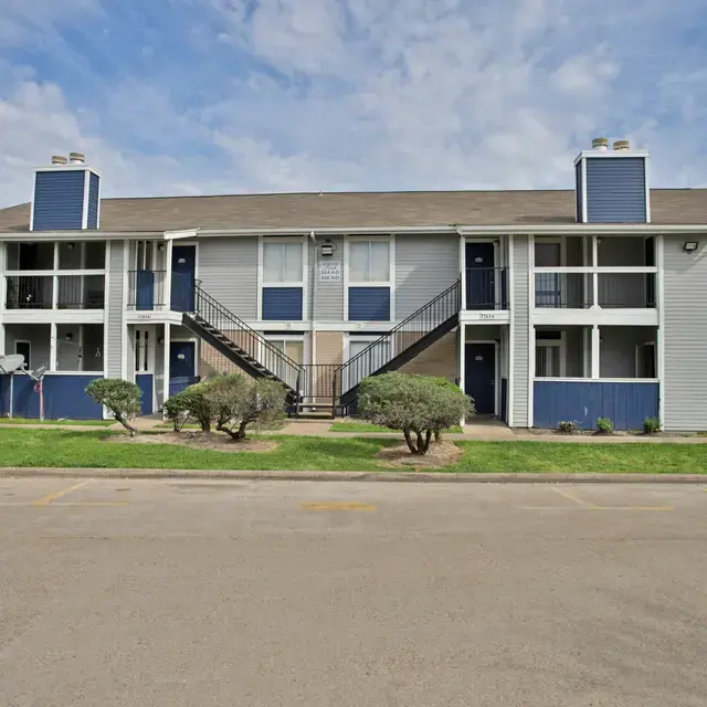 Two-Story Apartment Complex Two-story apartment complex with stairs, grass, and shrubbery in front.