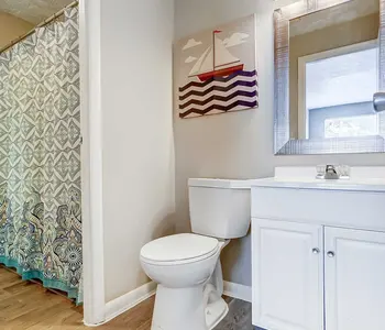 Contemporary bathroom with a white vanity, a toilet, and a decorative shower curtain.