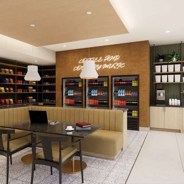 Interior of a modern coffee shop featuring a seating area, shelves of books, and a counter with colorful coffee supplies. The design includes wooden elements and bright lighting.