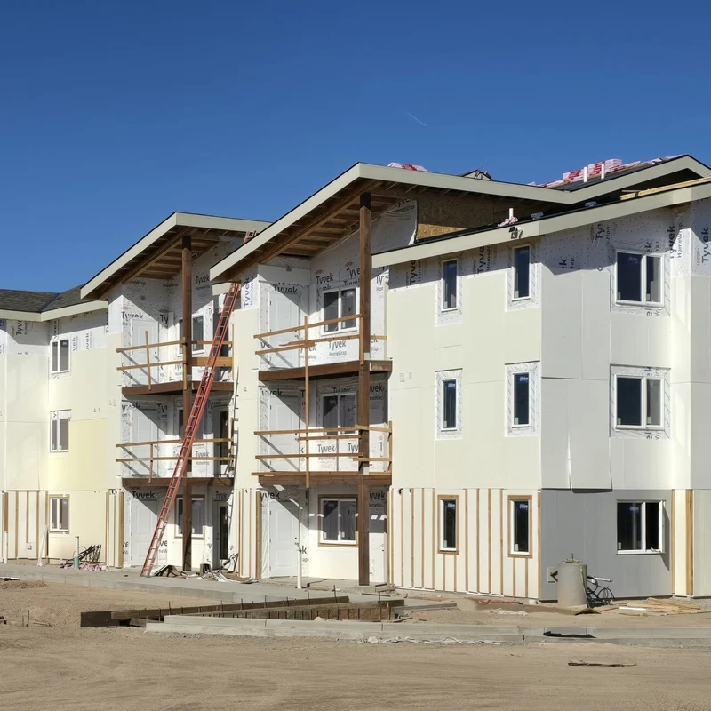 Construction of New Apartment Complex Newly constructed apartment buildings under construction with scaffolding and construction equipment visible.