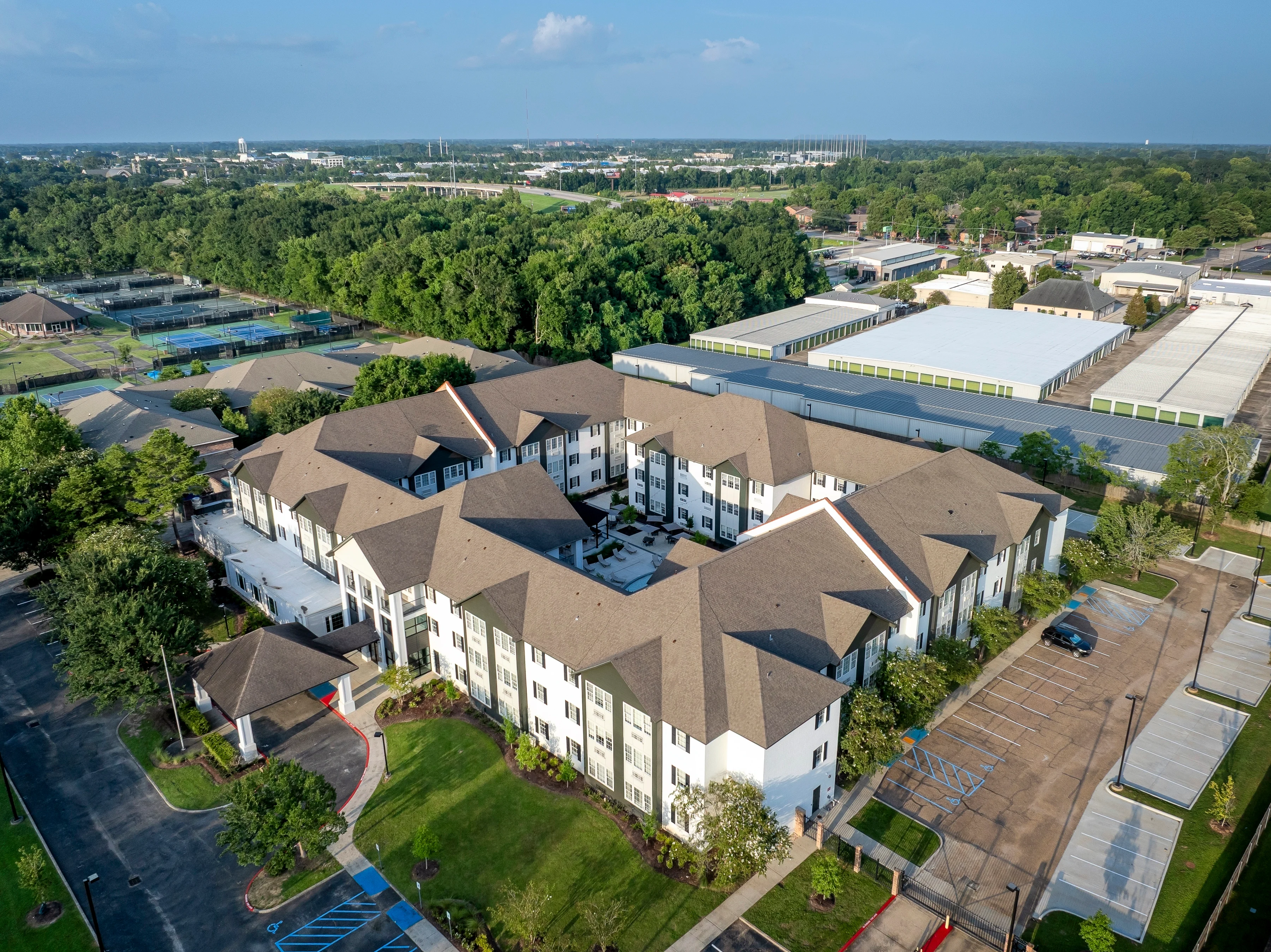 Aerial View of Modern Apartment Complex Aerial view of a modern apartment complex surrounded by trees and parking areas.