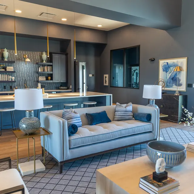 A stylish modern living room with a comfortable sofa and decorative accents, leading into a sleek kitchen area.