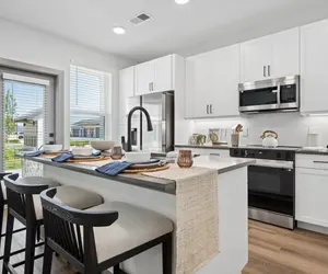 Contemporary Kitchen Design A modern kitchen featuring sleek white cabinetry, stainless steel appliances, and a breakfast bar with stools.