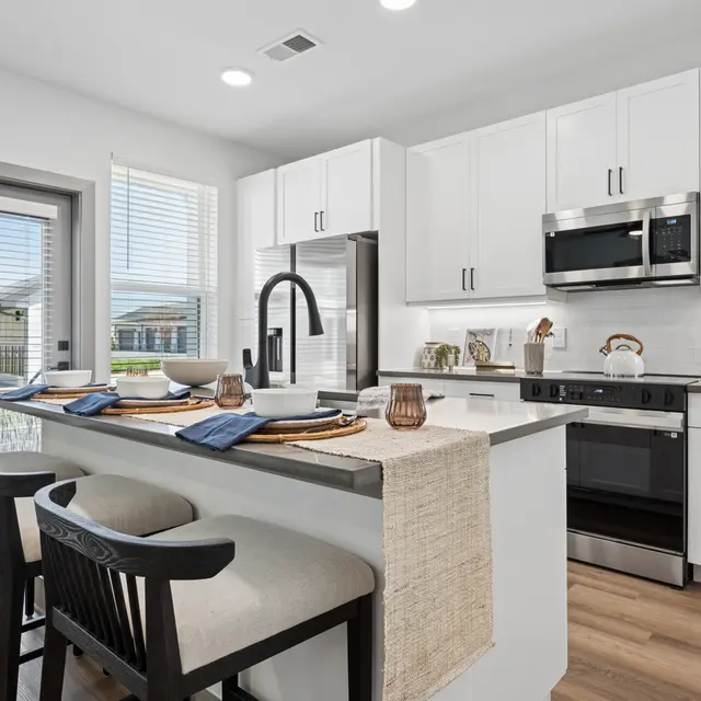 Contemporary Kitchen Design A modern kitchen featuring sleek white cabinetry, stainless steel appliances, and a breakfast bar with stools.
