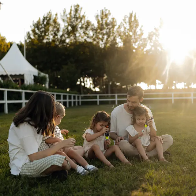 Family Bonding at Sunset A family sitting on grass during sunset, enjoying snacks together, with a warm glow from the sun behind them.
