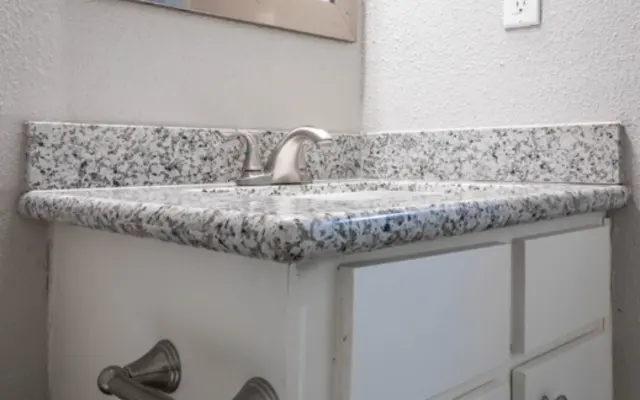 Modern Bathroom Vanity A close-up view of a bathroom vanity with a granite countertop, two faucets, and a white cabinet below.