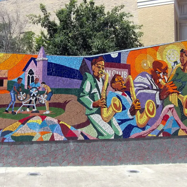 Vibrant mosaic mural depicting musicians playing instruments and community scenes with bright colors and abstract shapes.