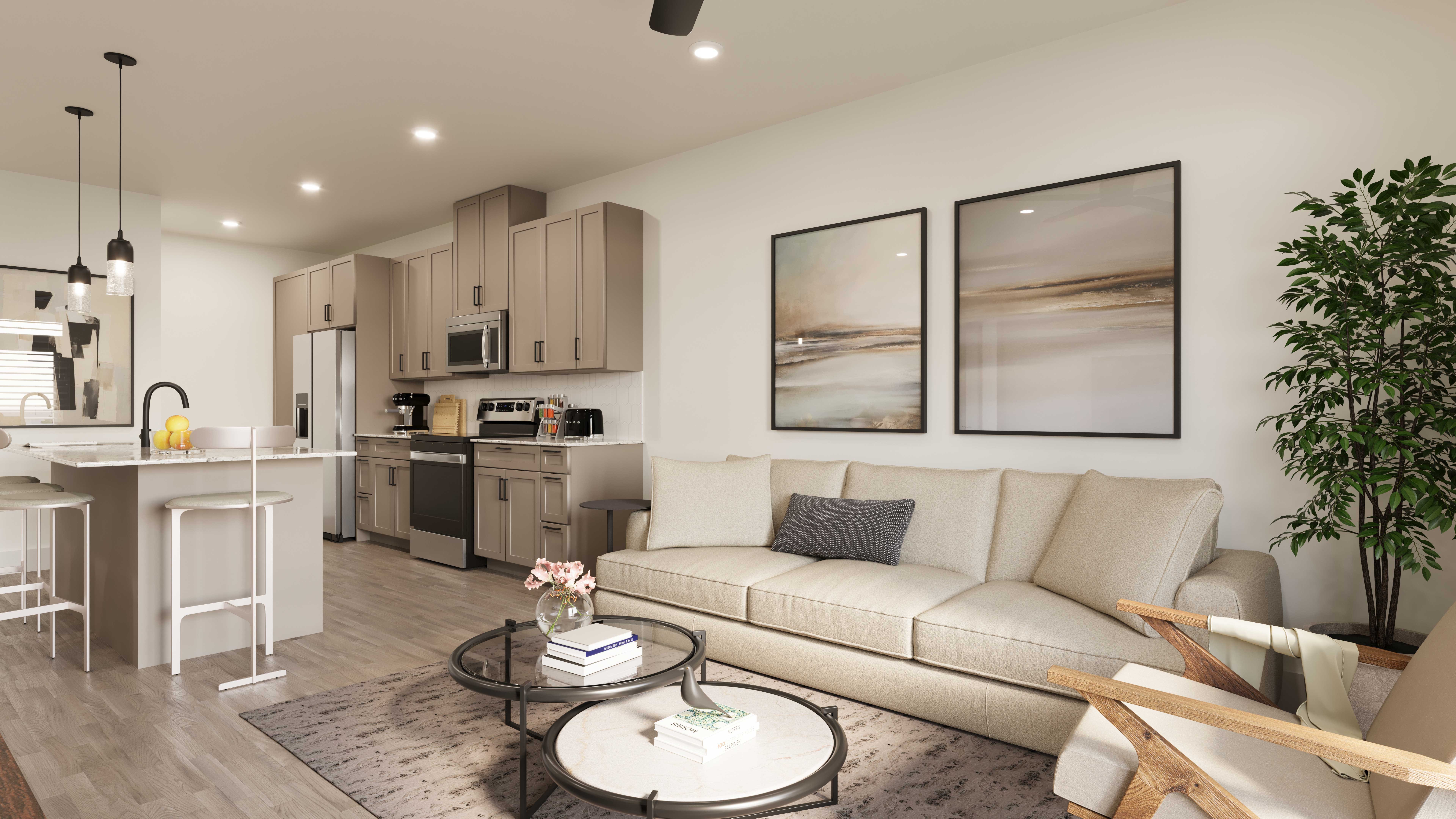 A modern living room featuring a sofa, coffee table, and kitchen area. The decor includes two framed paintings on the wall and a potted plant in the corner.
