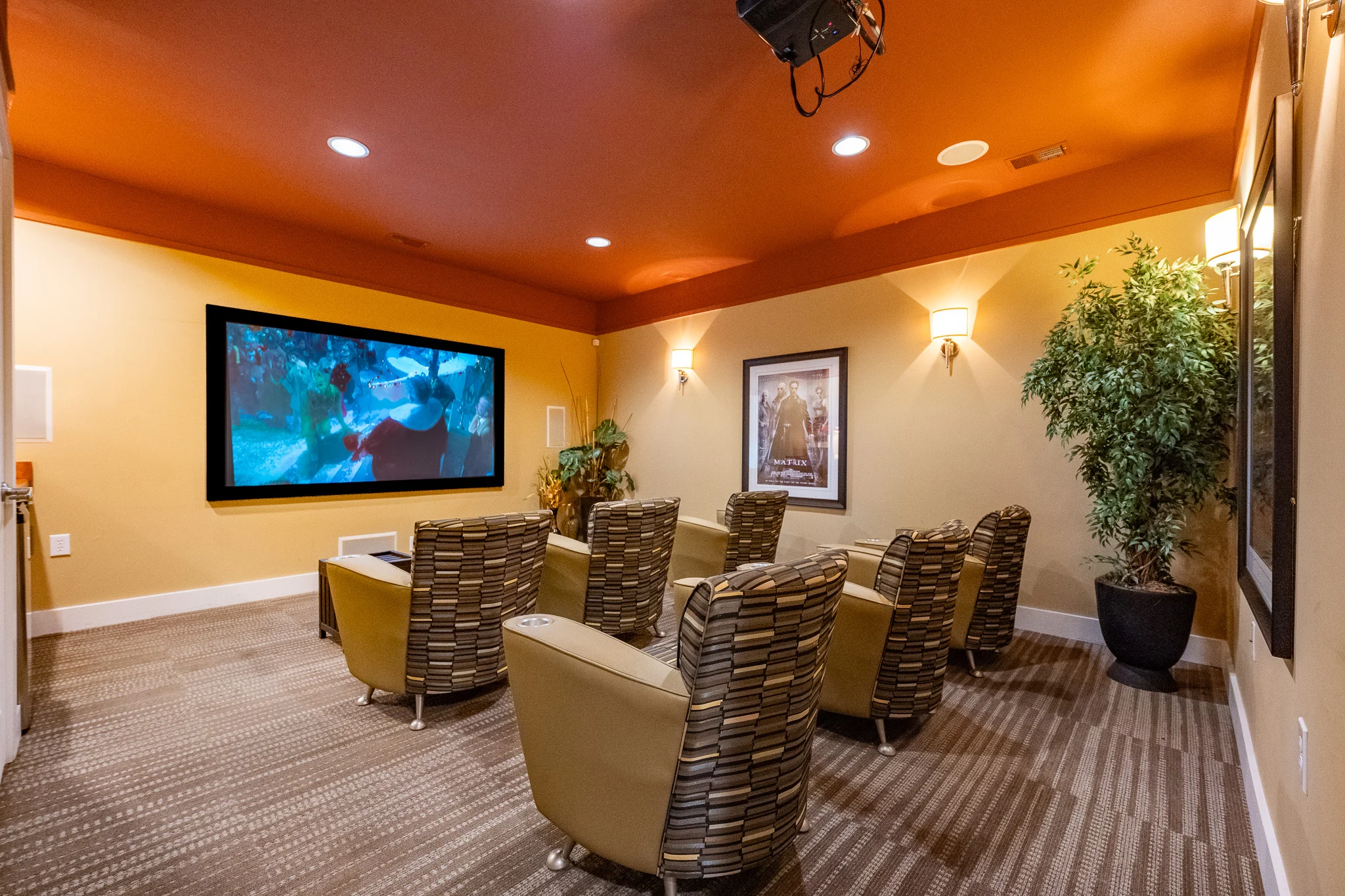 Cozy home theater room featuring a large screen, comfortable seating, and warm lighting.