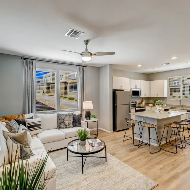 Modern open-concept living space with a cozy sofa, dining area, kitchen, and large windows letting in natural light.