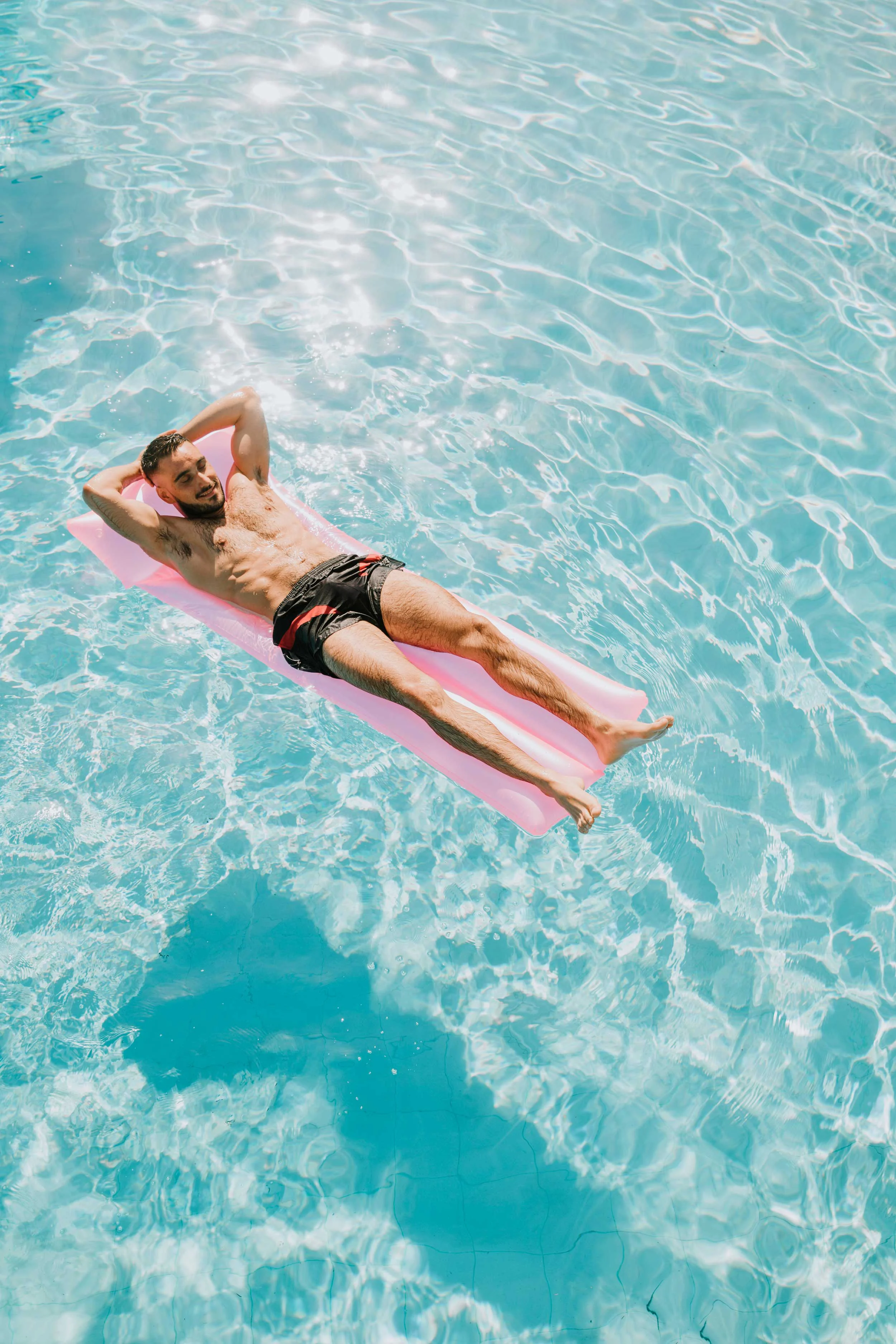 Summer Pool Relaxation A man relaxing on a pink float in a swimming pool