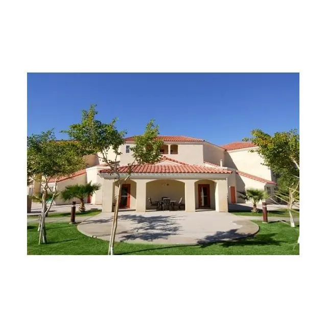 Charming House with Red-Tiled Roof A view of a house with a red-tiled roof, surrounded by greenery and a clear blue sky.