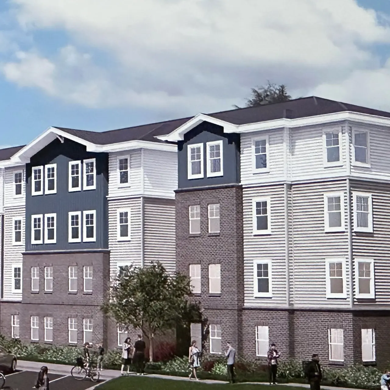 A modern apartment complex with a mix of dark and light colored siding, featuring multiple stories and landscaped grounds.