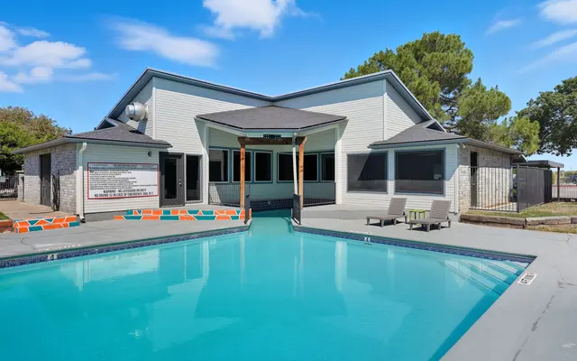Exterior view of a community pool area with a building in the background.