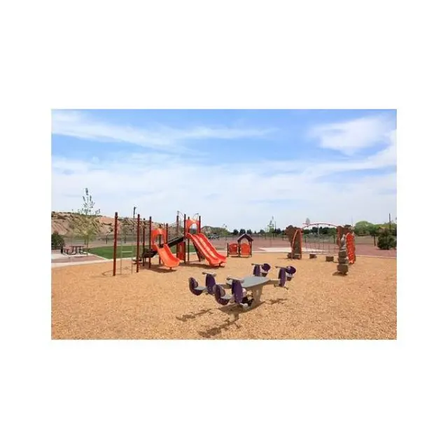Colorful Playground Scene A colorful playground with orange slides, purple swings, and a sandy surface under a clear blue sky.