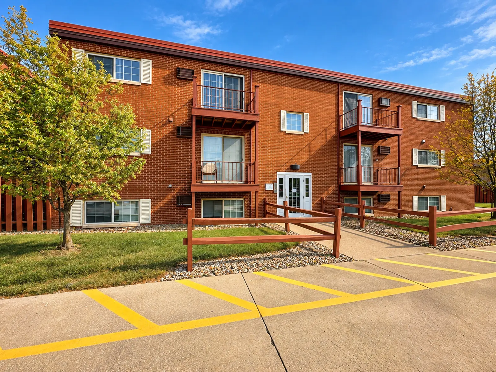 Exterior view of a brick apartment building with balconies and landscaped areas.