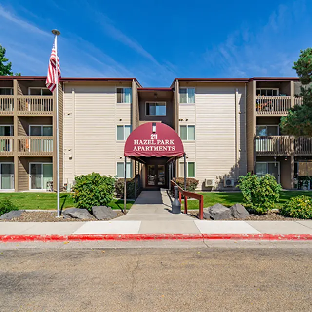 Exterior view of Hazel Park Apartments with visible landscaping and American flag.