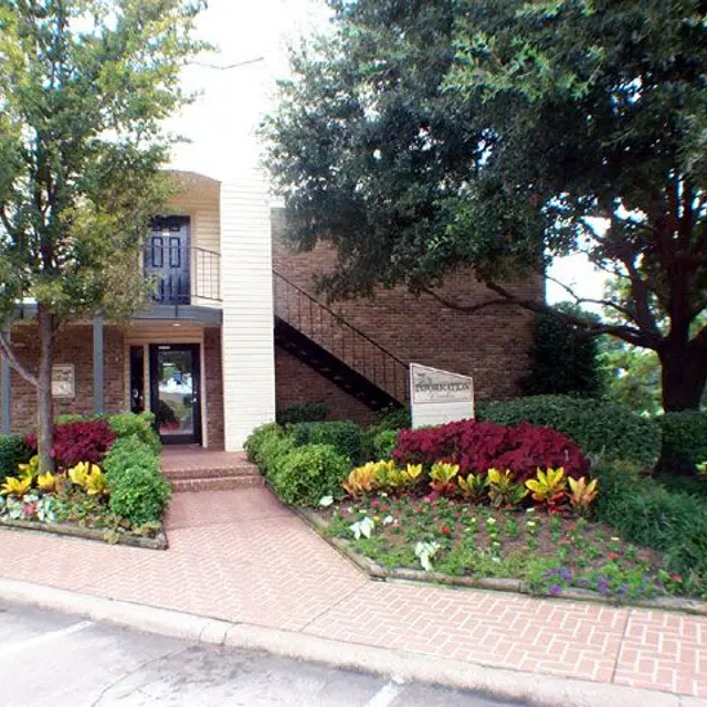 A welcoming entrance of a building featuring a staircase on the side and well-maintained flower beds.