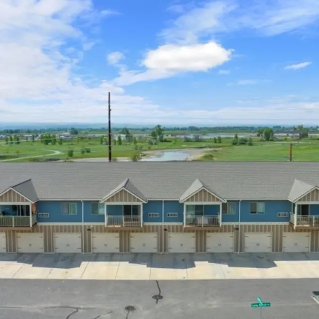 Granite Peak Aerial view of a residential building with multiple units, featuring a row of garages at the front and green fields in the background.