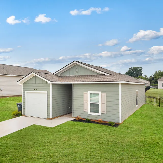 Charming Single-Story Home A view of a modern, single-story home painted in light green with a garage and white trim, set in a grassy yard on a sunny day.