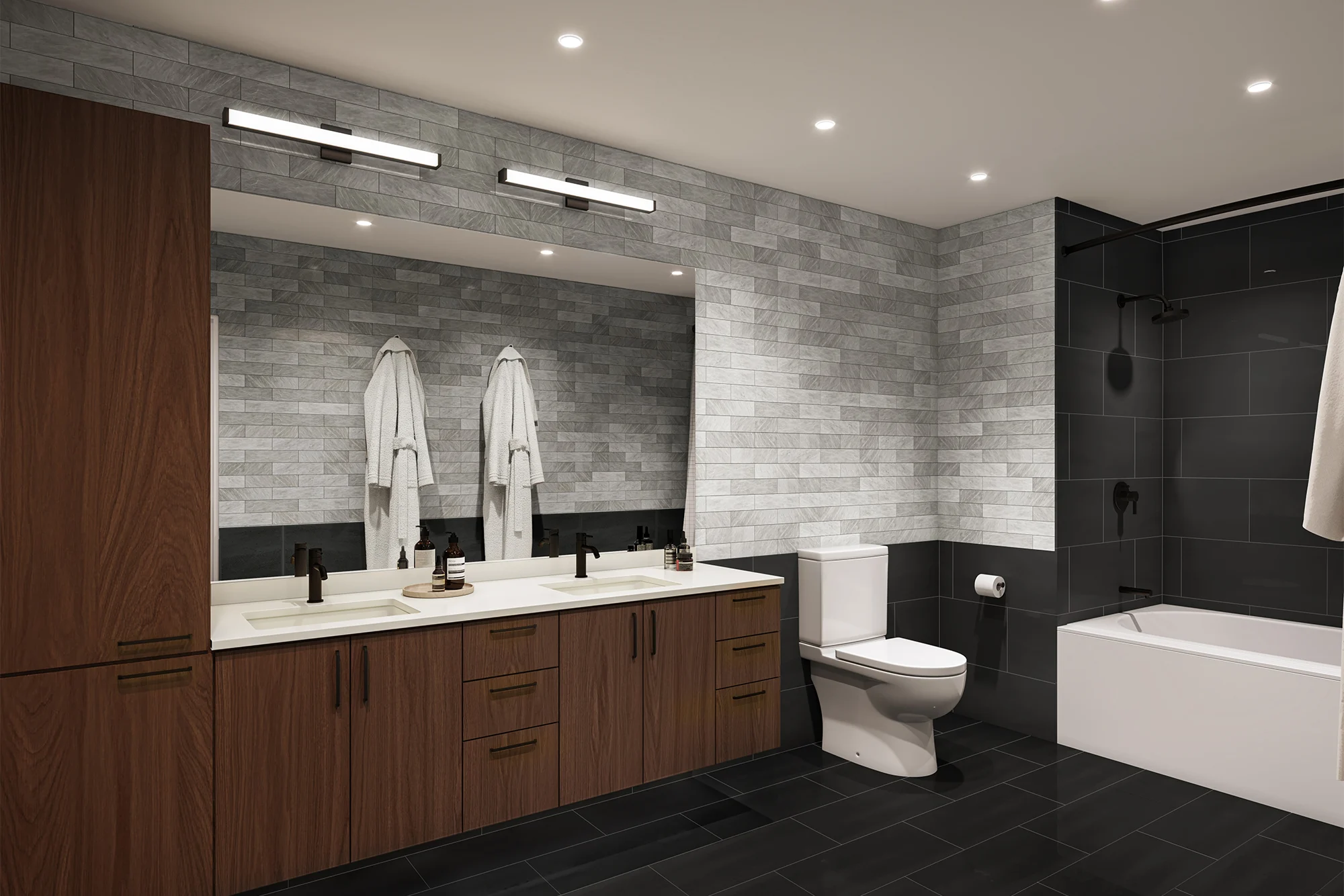 A modern bathroom featuring a spacious vanity with a double sink, dark wooden cabinets, and a large mirror. The walls are adorned with grey bricks, and there are two white bathrobes hanging. The bathroom includes a white toilet and a bathtub against a dark tiled wall.