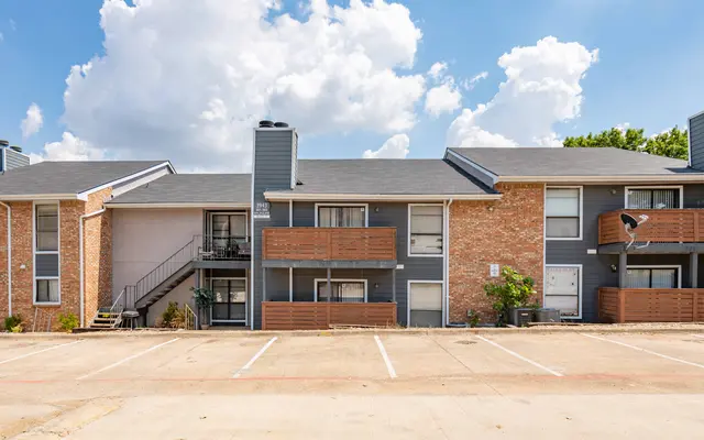 Exterior view of an apartment complex featuring multiple units with balconies and a staircase.