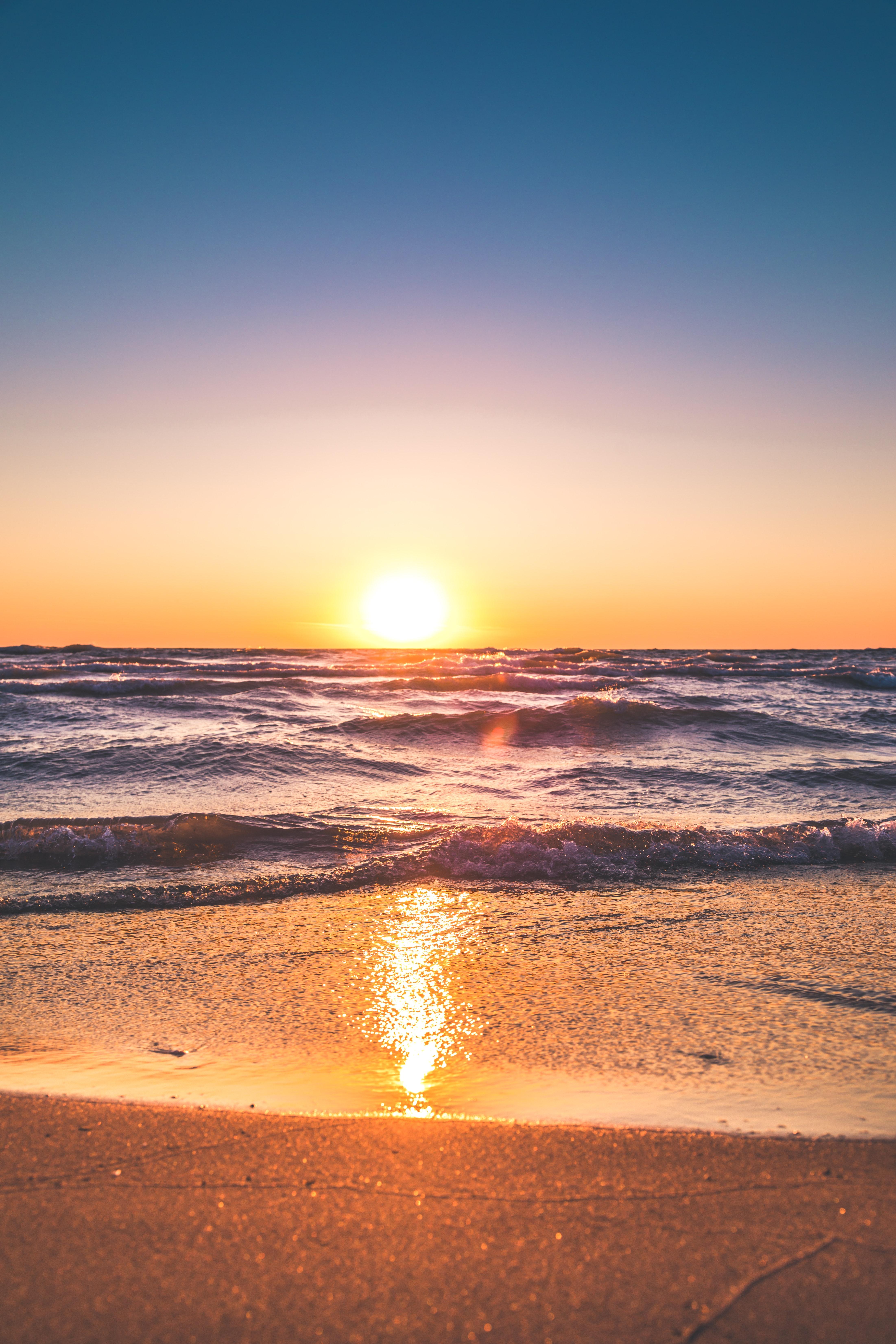 A serene sunset over the ocean with gentle waves reflecting the warm colors of the sky.