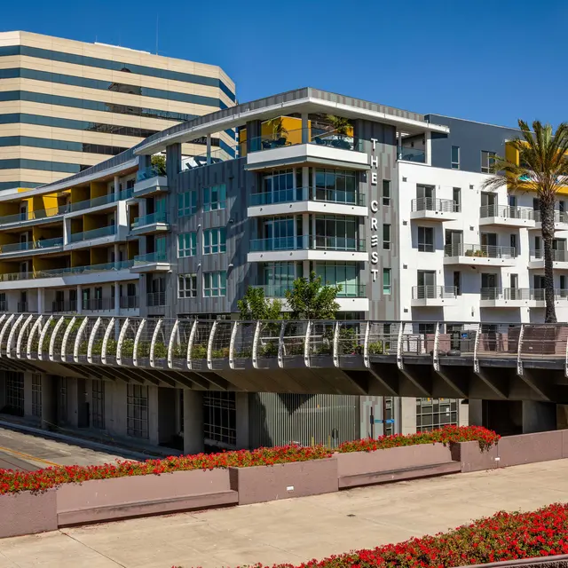 Modern Urban Apartment Complex A modern urban apartment building with a distinctive architectural design, featuring multiple stories, balconies, and palm trees in the foreground.