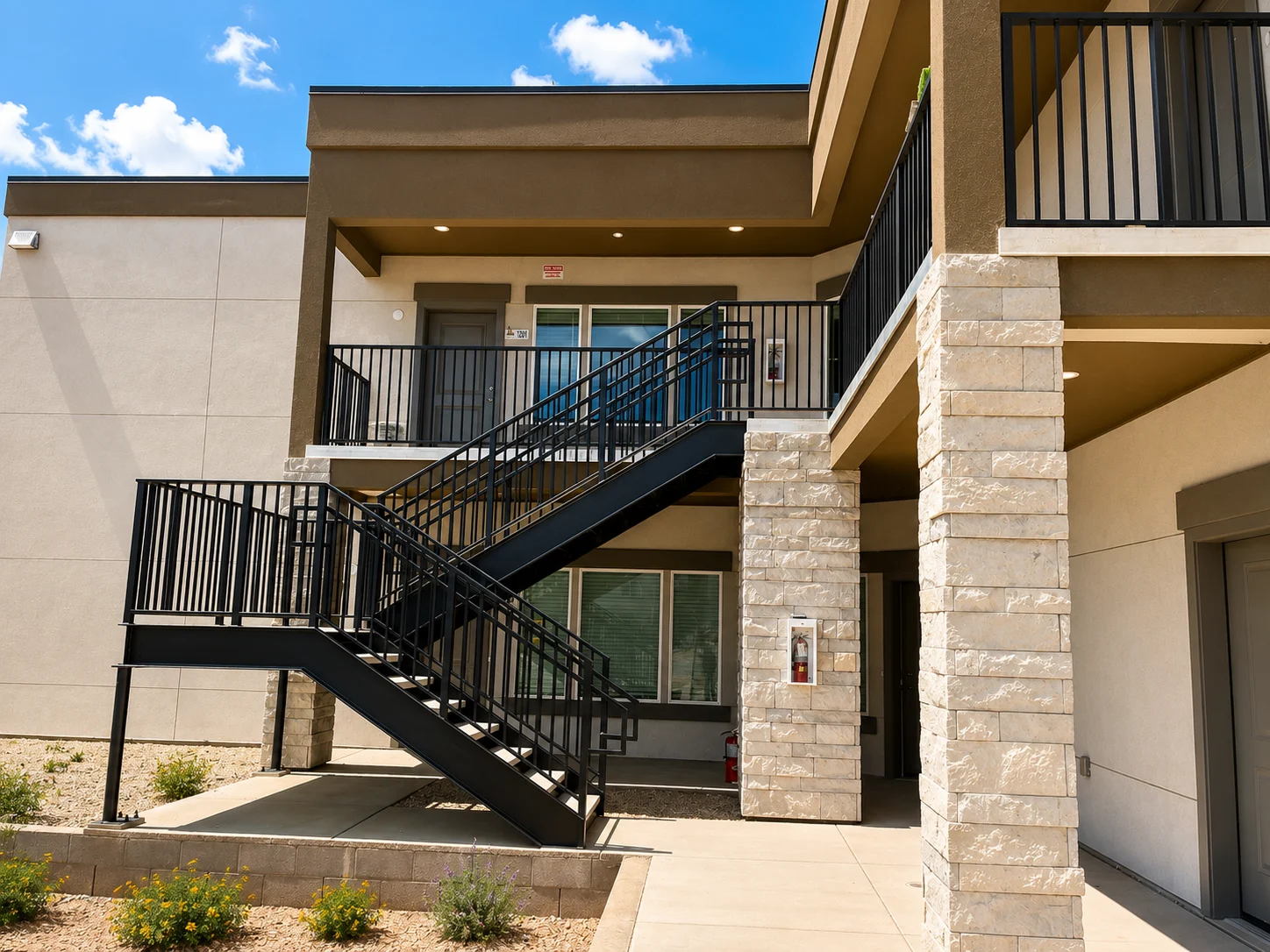 Exterior view of an apartment building featuring a staircase and landscaped area.