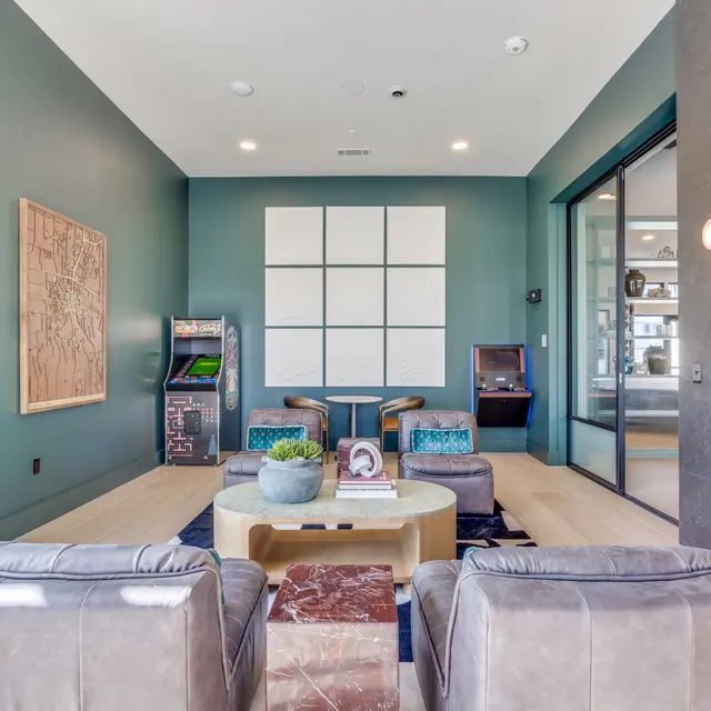 A modern lobby area with green walls, comfortable seating, and a decorative wall art piece.